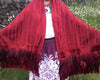 Rebozo artesanal rojo con plumas de gallo decorando las puntas